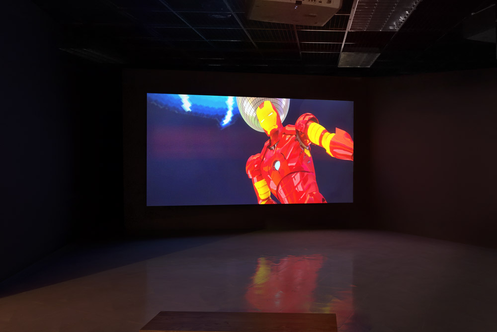 video installation in gallery showing still from Monaghan's video installation showing marvel's iron man dancing against a blue night sky.