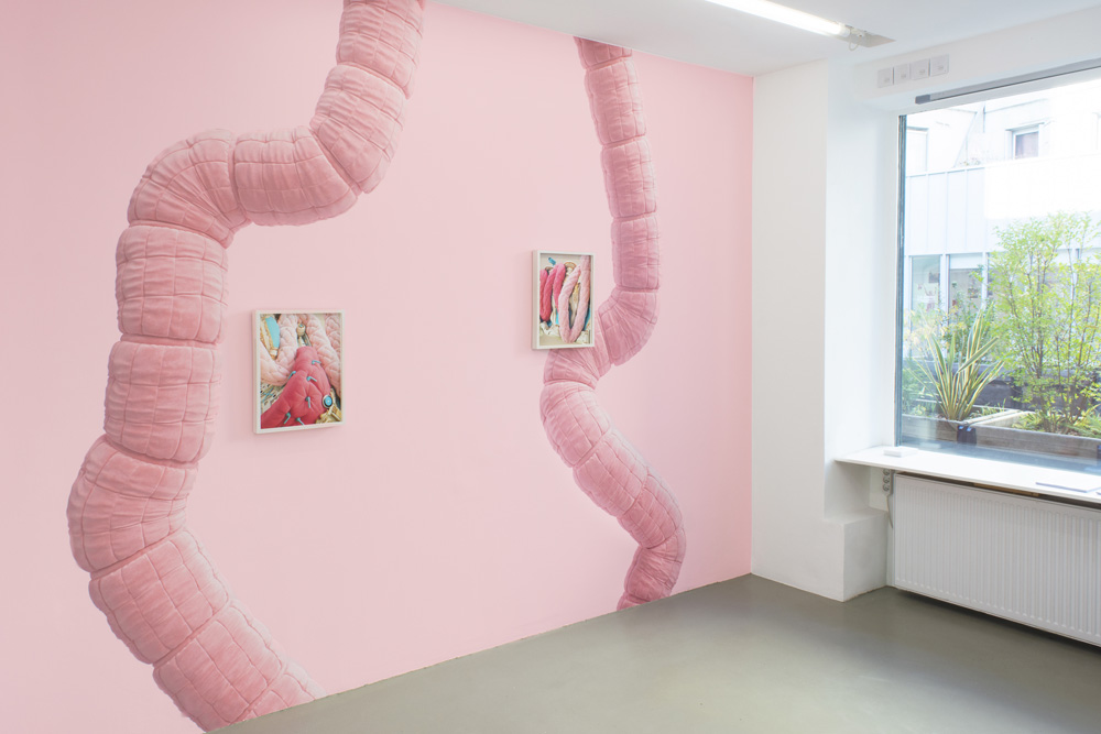 Wall decal by Jonathan Monaghan features strange electronic devices juxtaposed near colorful soft fabrics.